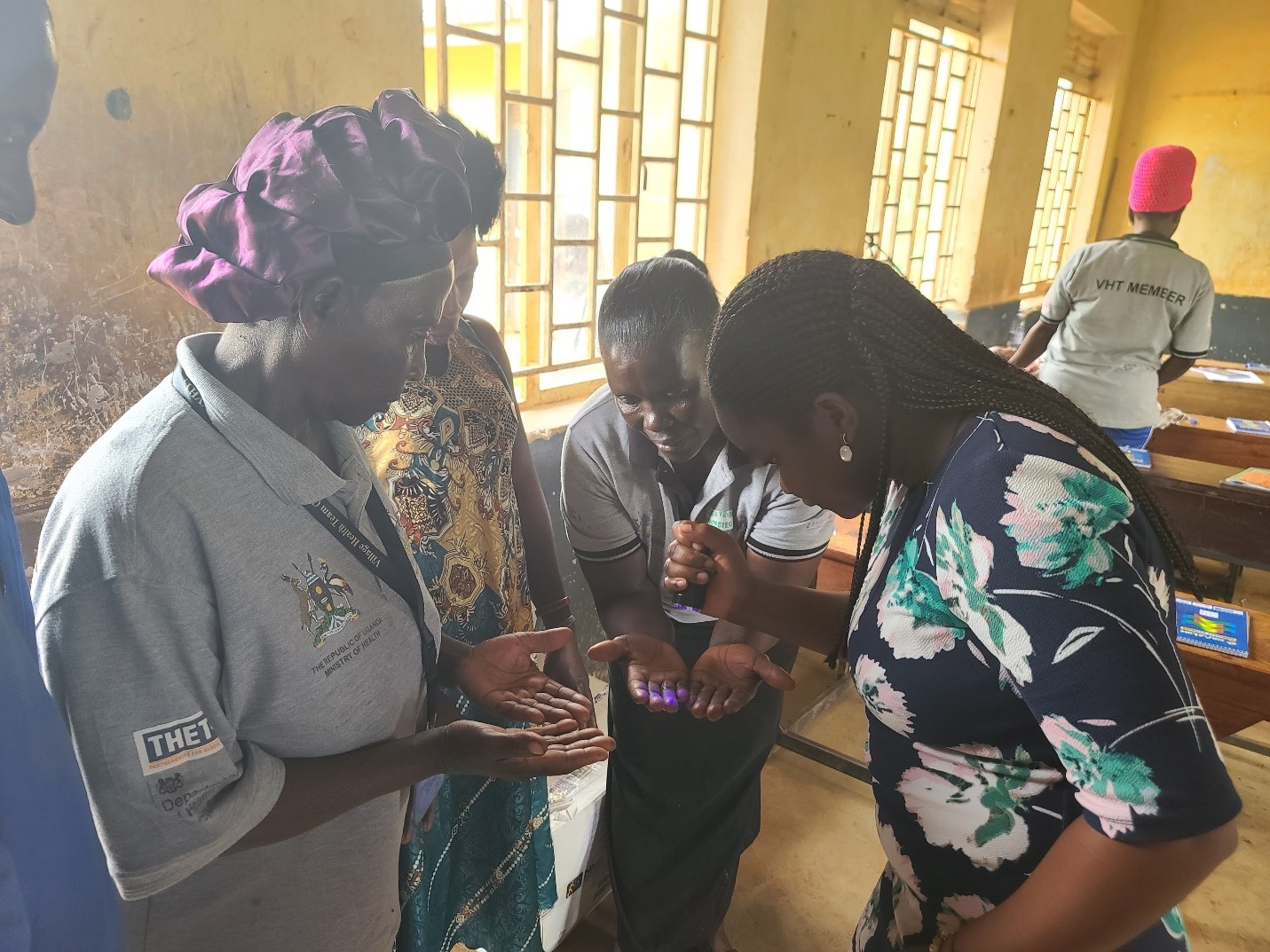Carol Esther Nabbanja, a project team member guiding CHWs through the glow germ handwashing activity during their AMS training at Mpiringisa Church of Uganda in Kyengera Town Council.