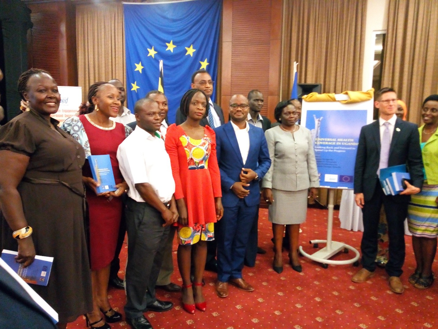 Some of the 30 author team pose for a photograph besides the book dummy together with Hon Opendi and Mr. Tiedemann