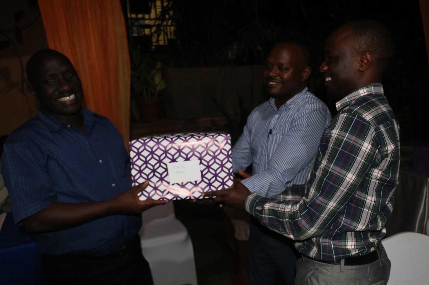 Dr. Vincent Kiberu (Left) receives a gift organized by the PhD Forum from other staff of Makerere University School of Public Health. Middle is Dr. John Bosco Isunju and Dr. Moses Tetui