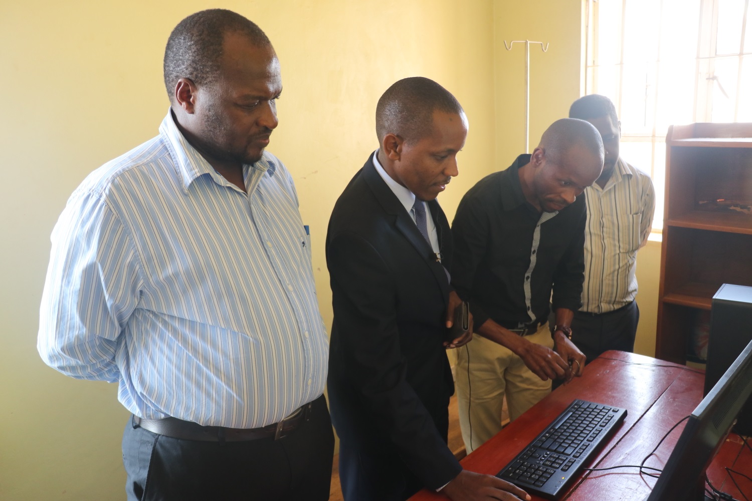 Dr. Kasirye Geoffrey (left), the Medical Officer of Mukono Health Centre IV looks on as Dr. Musinguzi Geofrey (Centre) trains a Health Worker on data entry at Mukono Health Centre IV