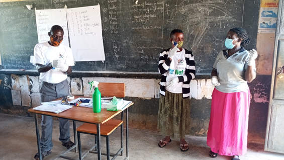 Village Health Team members in Zzinga island carrying out a role play demonstrating the proper use gloves as part of Personal Protective Equipment