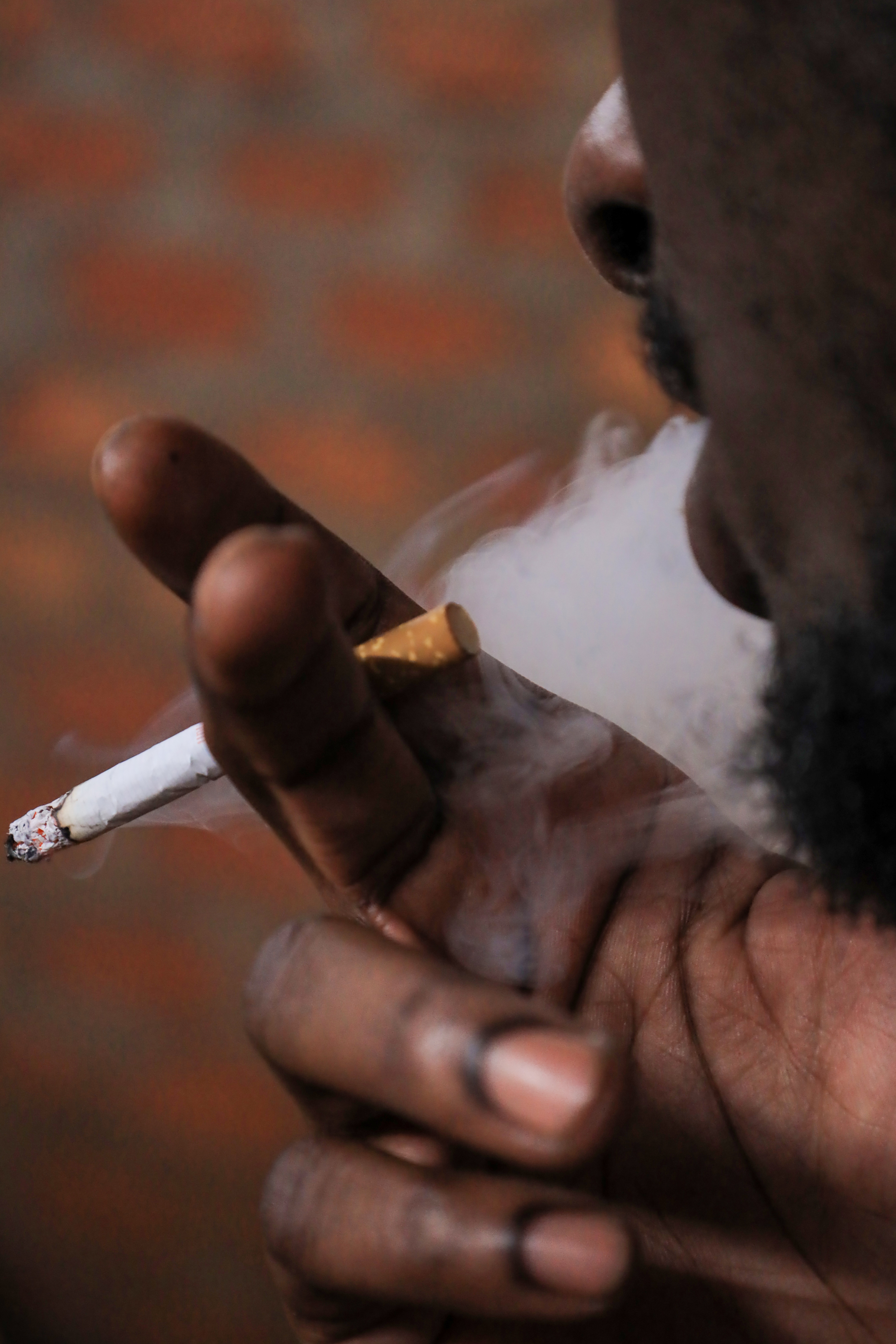 A young man smokes cigarettes in Makerere Kikoni, a neighborhood bordered by Bwaise to the north, Makerere University to the east, Naakulabye to the southwest. Formerly a slum in semi permanent structures, it is now most developed with student hostels.