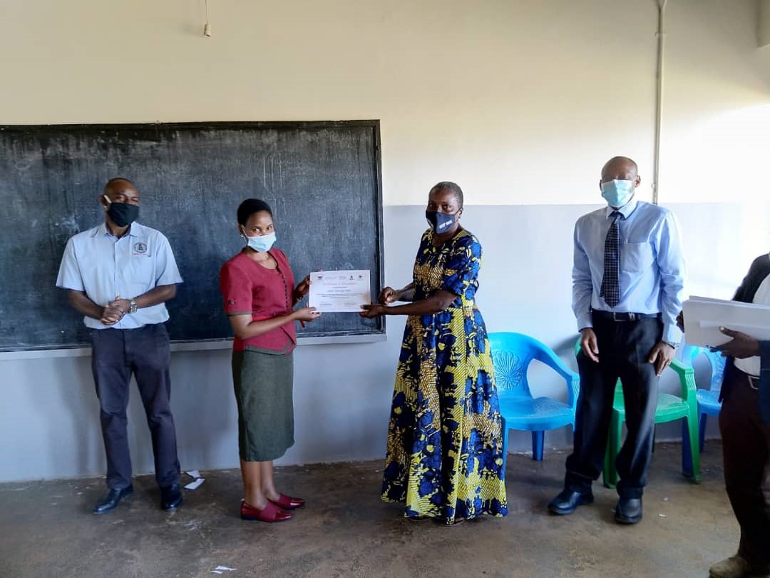 Ms. Bonny Natukunda (2nd left), the Senior District Health Educator, Wakiso district awarding a certificate to a VHT as Dr. John Kalyesubula (Medical Officer of Health, Entebbe Municipality - extreme left) and Dr. David Musoke (Project Lead from Makerere University School of Public Health – extreme right) look on during the closing ceremony at the training in Division A, Entebbe Municipality.