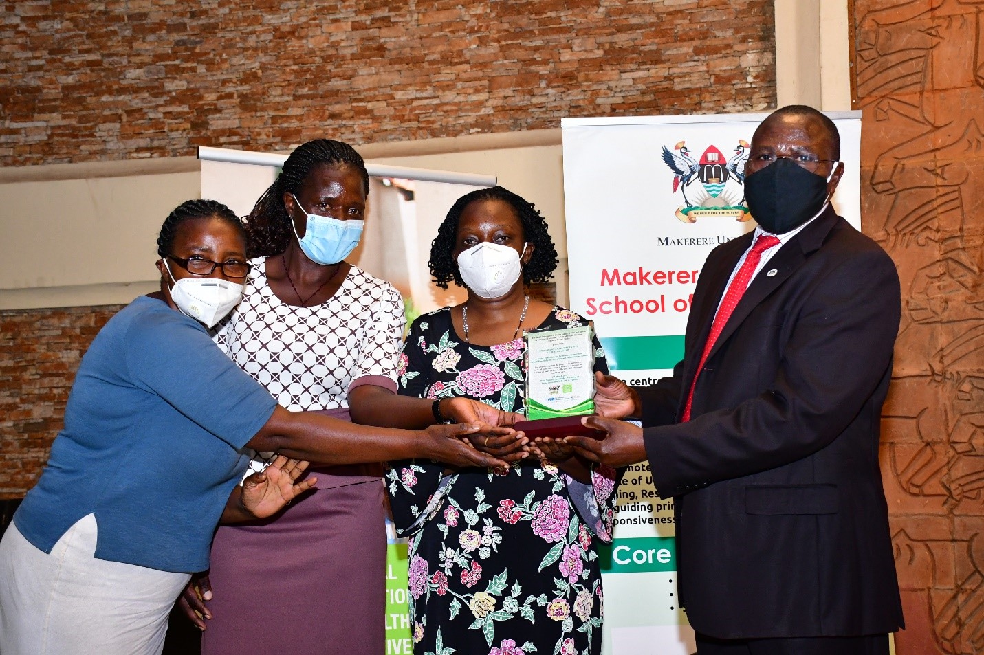 Dr. Maxwell Otim Onapa, the Director of Science, Research and Innovation at Ministry of Science, Technology and Innovation hands over a plaque to Dr. Etheldreda Nakimuli and her team at SEEK-GSP project. Their project aimed at narrowing the treatment gap for depression among people living with HIV using group support psychotherapy delivered by community health workers. They are among the winners of the 2020 Social Innovations in Health Awards organized by the School of Public Health. 