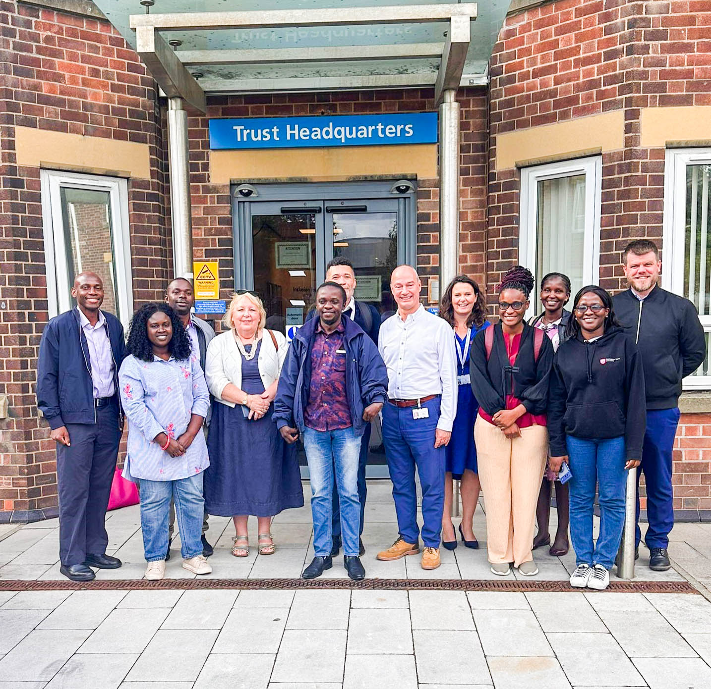 A group photo at the Nottingham University Hospitals Trust Headquarters with Nick Carver (in white shirt) - the Chair of the Trust Board, Lisa Kelly (in blue dress) - the Chief Operating Officer of the Trust, Russell Pitchford (in black coat) and Mr. Richard Holder (at the back).