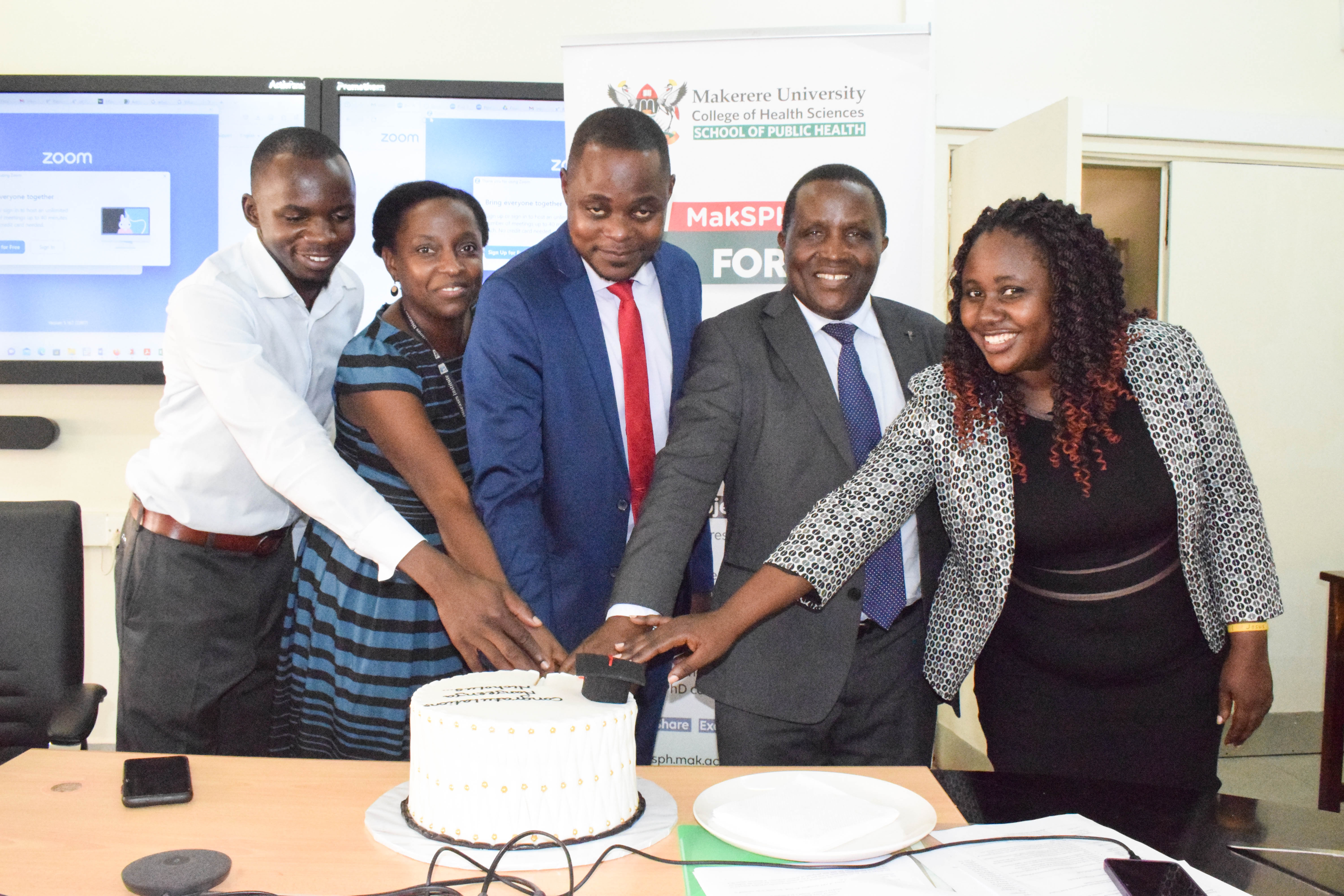 Dr. Nicholas Nanyeenya cuts cake shortly after his PhD Defense on Thursday, December 7, 2023.
