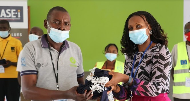 Dr. Gloria Seruwagi handing over masks to the Chairman of Kyaka II Refugee Settlement in Kyegegwa