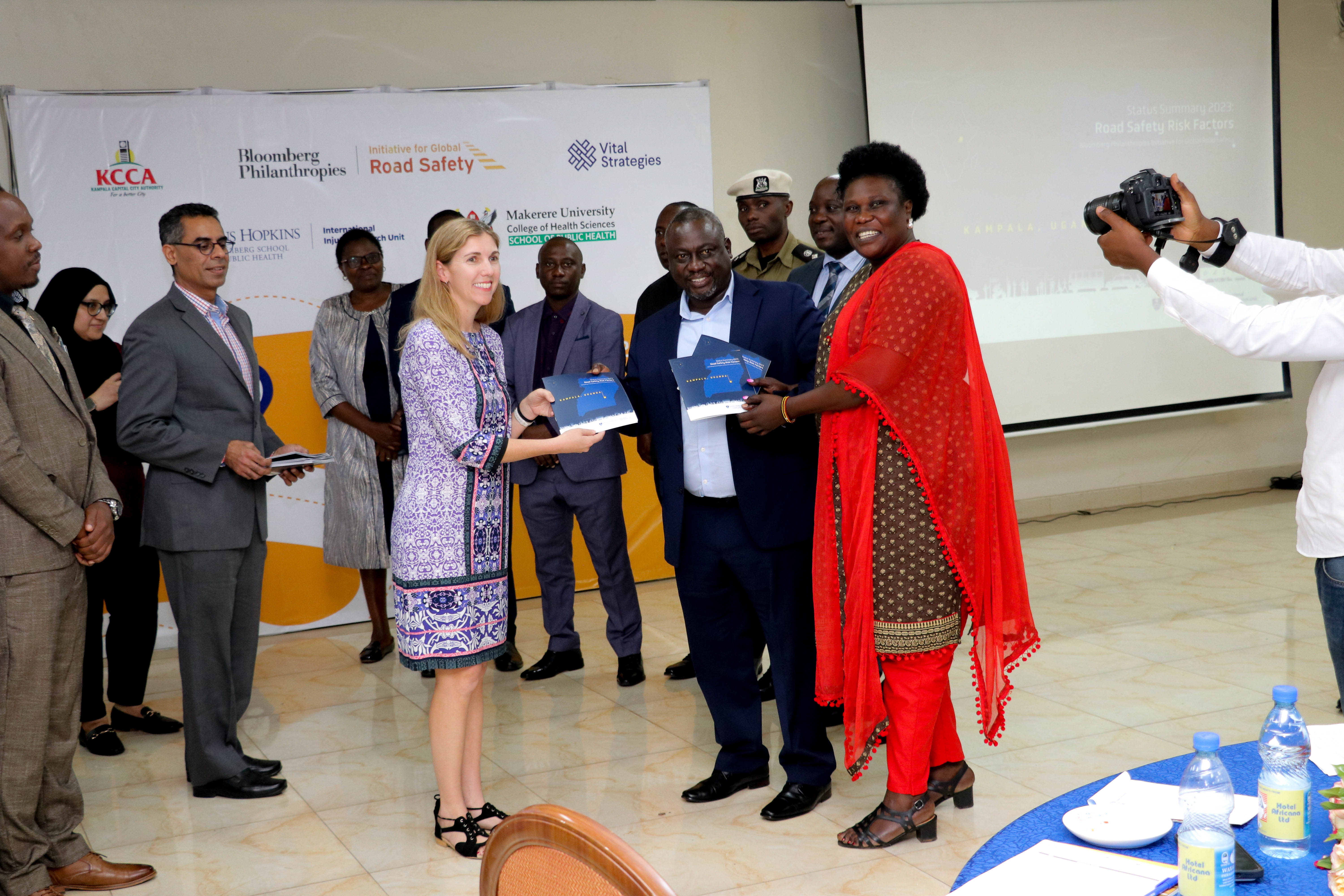 Becky Bavinger, from the public health area of Bloomberg Philanthropies hands a copy of the Kampala Summary Status Report on Road Safety Risk Factors to KCCA 