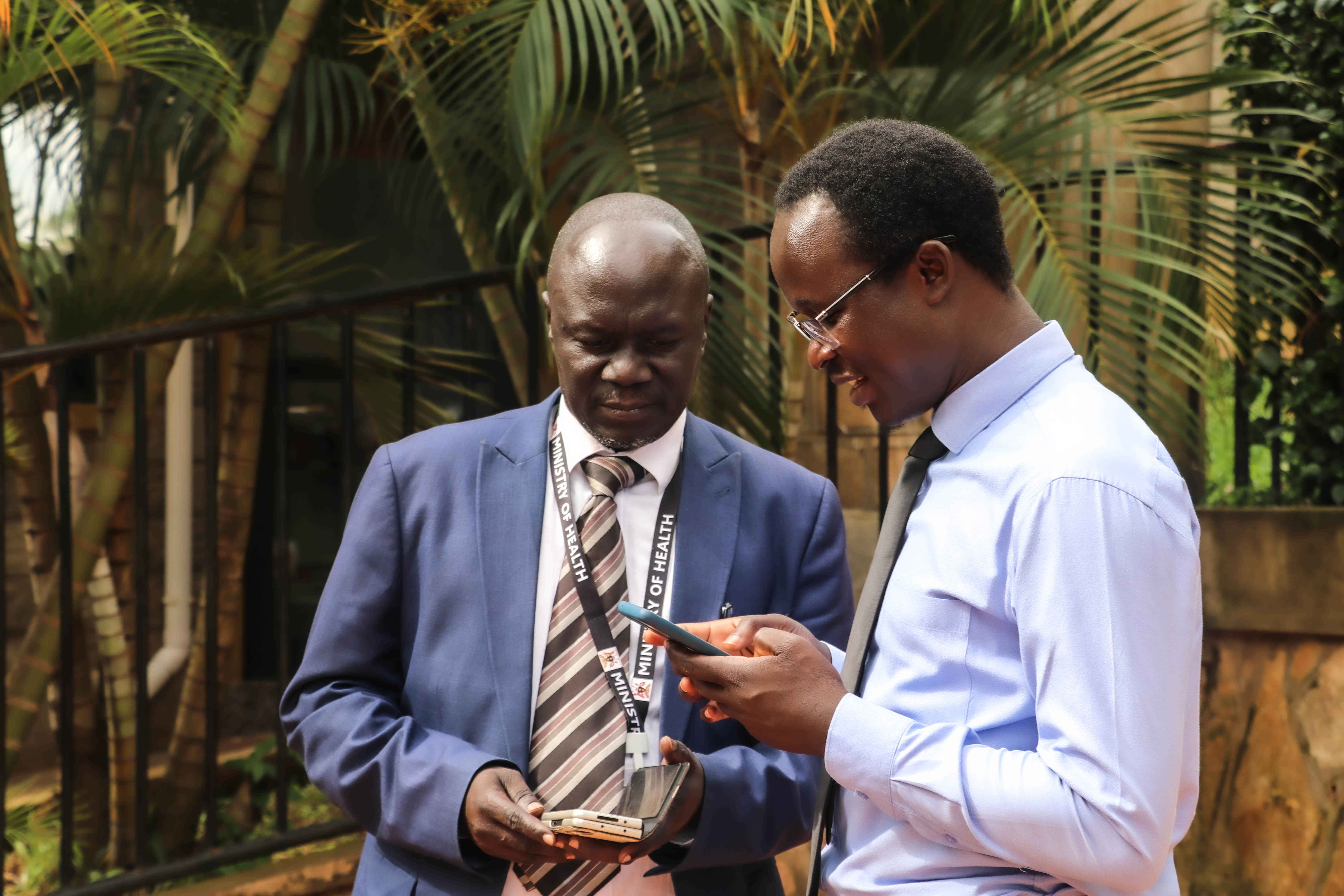 Dr. Simple Ouma from TASO Uganda exchange contacts with Dr. Ronald Miria Ocaatre, the Acting Assistant Commissioner Health Promotion, Education and Communication, Ministry of Health shortly after the event.