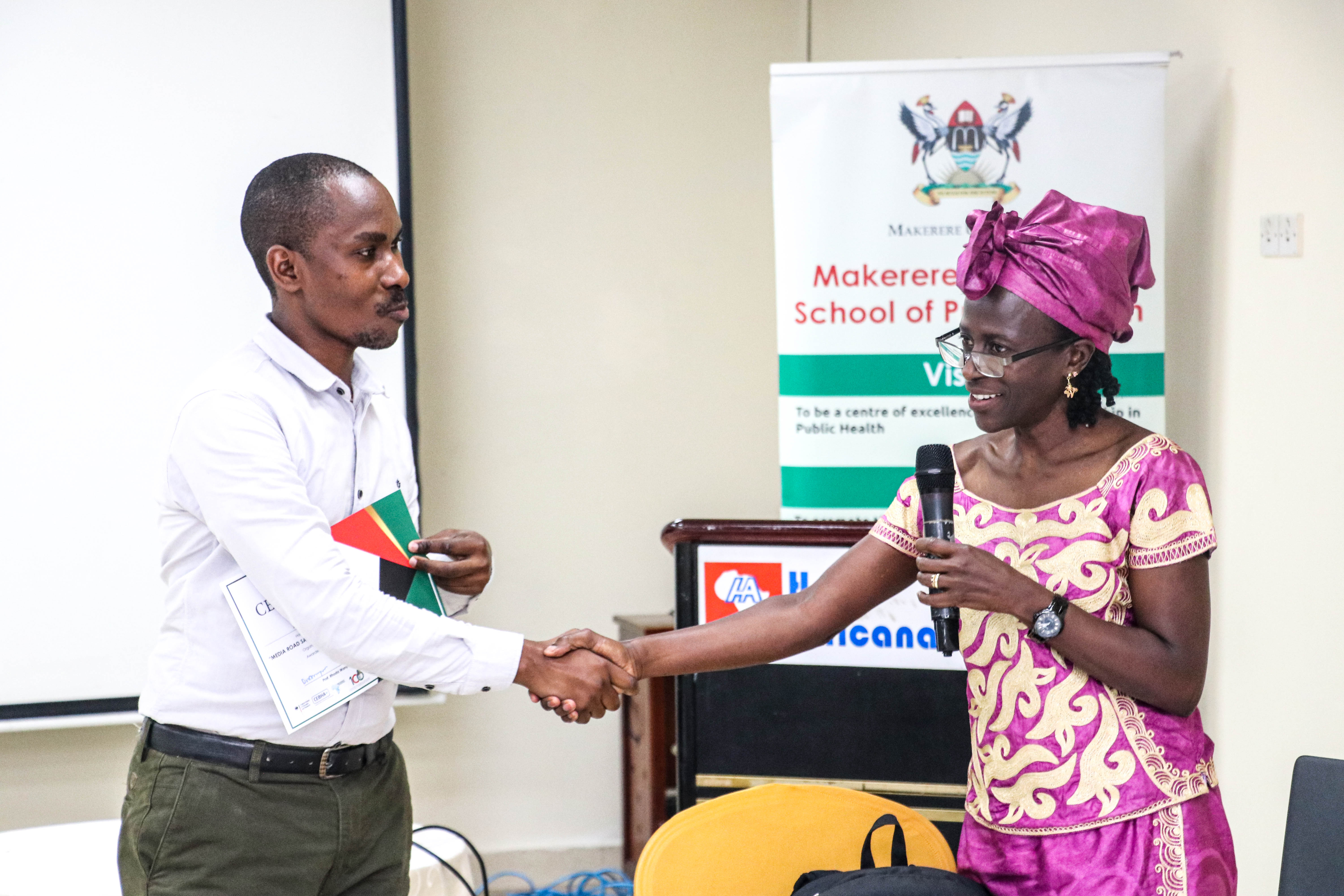 Mr. Ronald Musoke receives a certificate from Dr. Olive Kobusingye