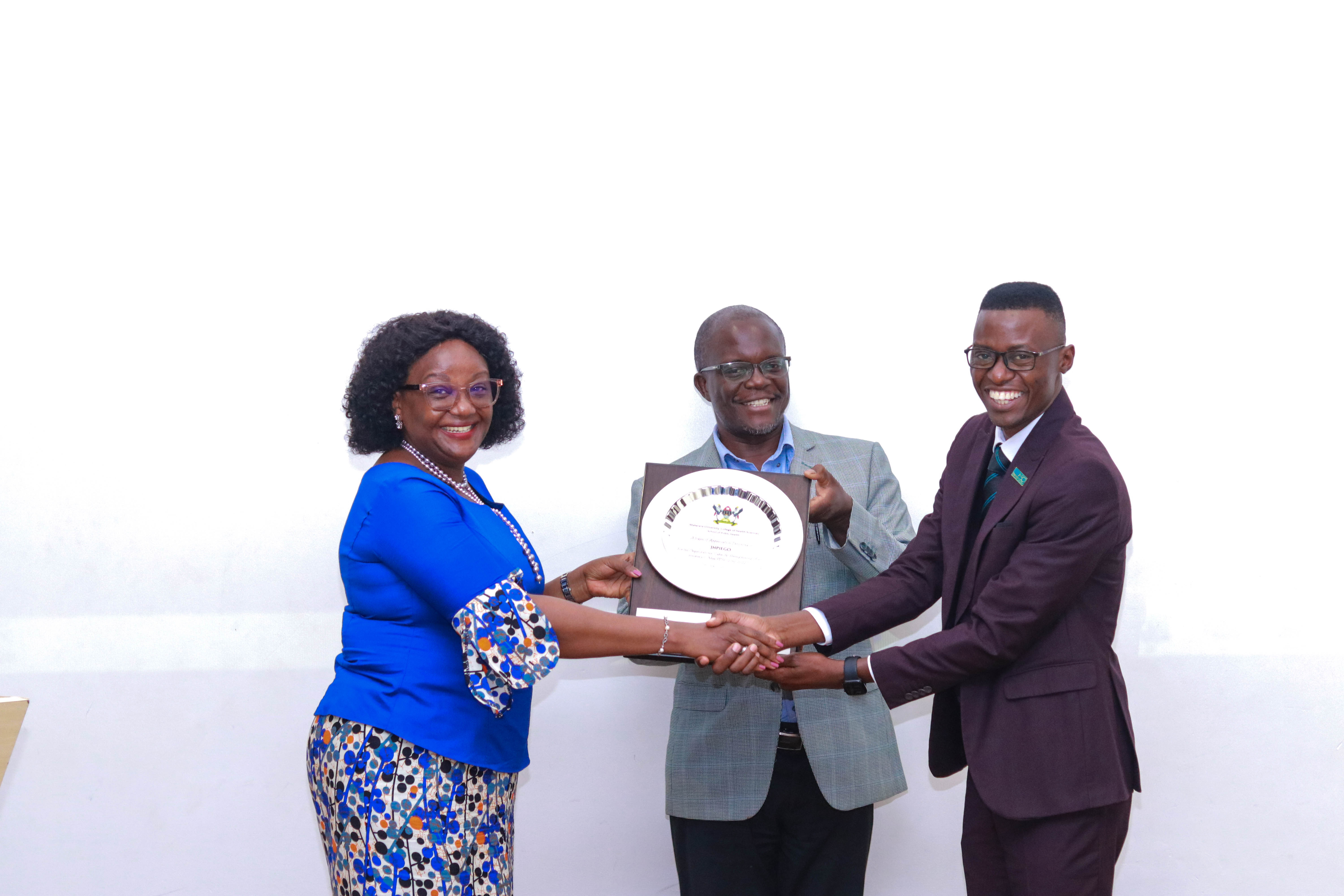 Dean, MakSPH, Prof. Rhoda Wanyenze alongside PMA Principal Investigator Prof. Frederick Makumbi hands over a plaque to Jhpiego Uganda Country Manager Dr. Martin Ndifuna in appreciation of their support towards the OCA. 