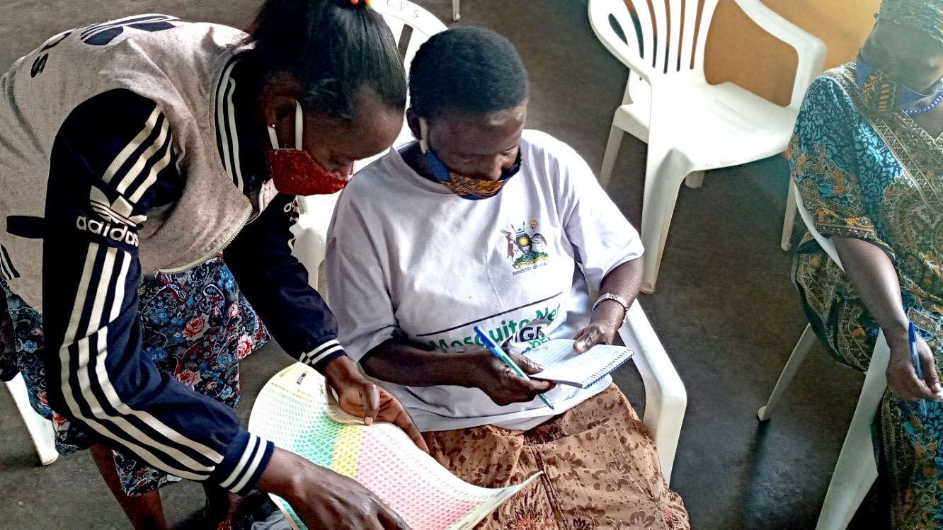 Ms. Barbra Ajuna Nelly (left), a health worker explaining how to use a BMI Chart to a VHT (right) during a training in Entebbe Municipality.