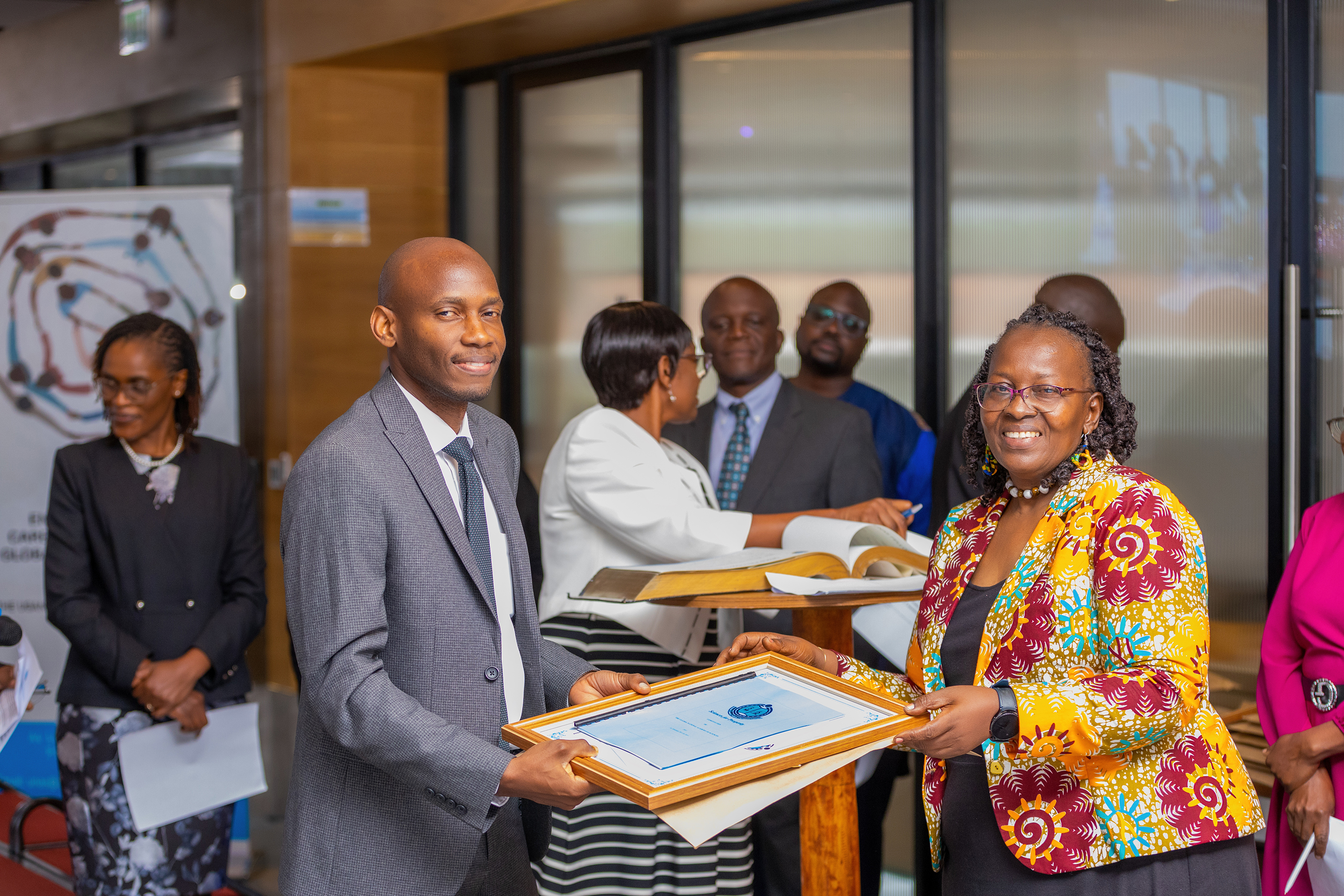 Dr. David Musoke receives a certificate and fellowship membership instruments shortly after oath taking.