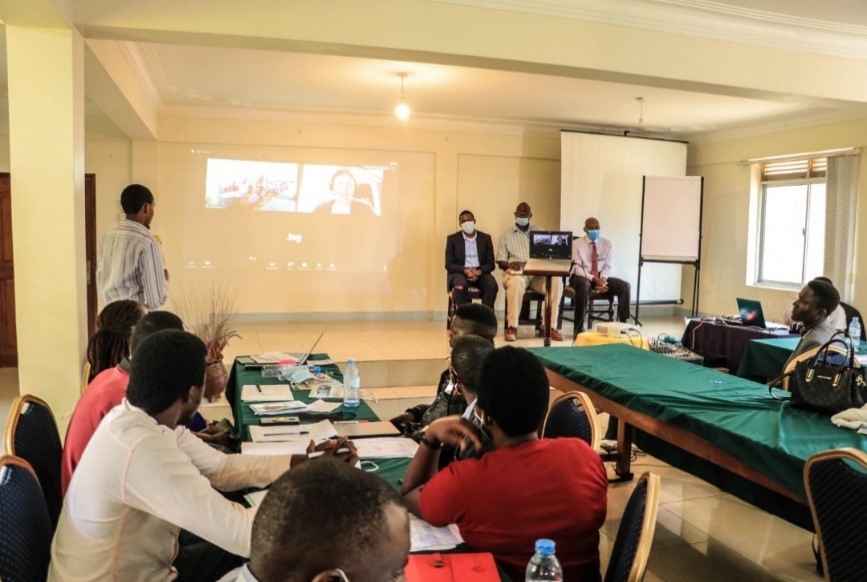 Mr. Filimin Niyongabo from MakSPH (standing) and Dr. Jody Winter from Nottingham Trent University (on screen) facilitating a blended AMR / AMS / IPC workshop for private pharmacy staff, lower-level health facility workers, and veterinary officers in Entebbe.