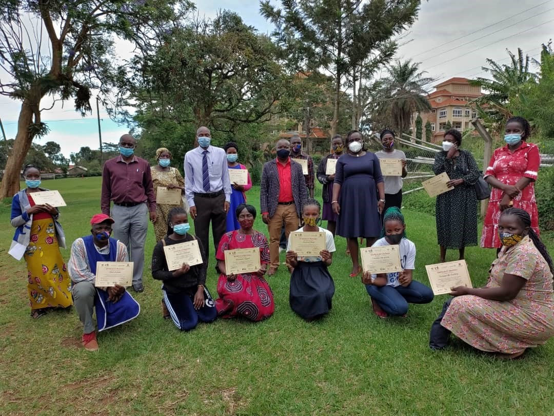 Some community health workers pose with their certificates for a group photo with Dr. David Musoke (in blue shirt and tie) following a training on AMR / AMS / IPC.
