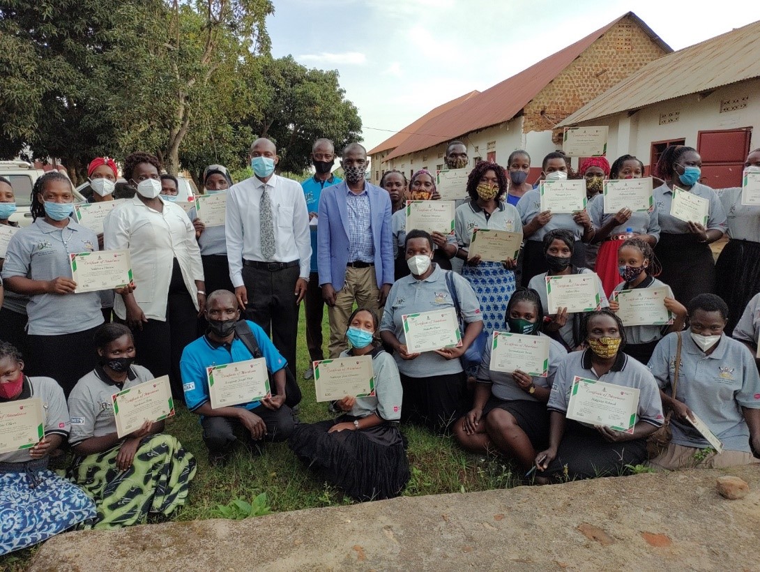 Dr. David Musoke (with tie) standing with health practitioners as VHTs display their certificates following the 2-day training in Kyengera Town Council, Wakiso District.