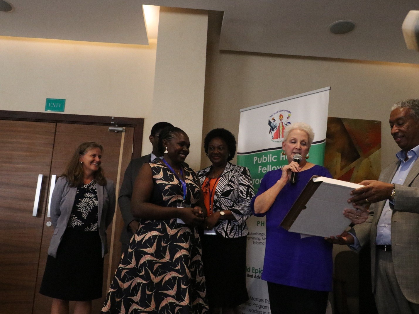 Ambassador Malac (second left) reads from a plaque that was awarded to Dr. Kizito (second right) who was voted as the most outstanding fellow by her colleagues