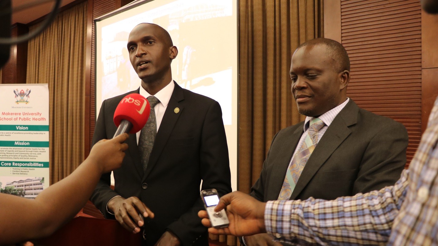 Dr Simon Peter Kibira (black suit) and Dr Frederick Makumbi (dark grey suit) answer press questions at the dissemination.