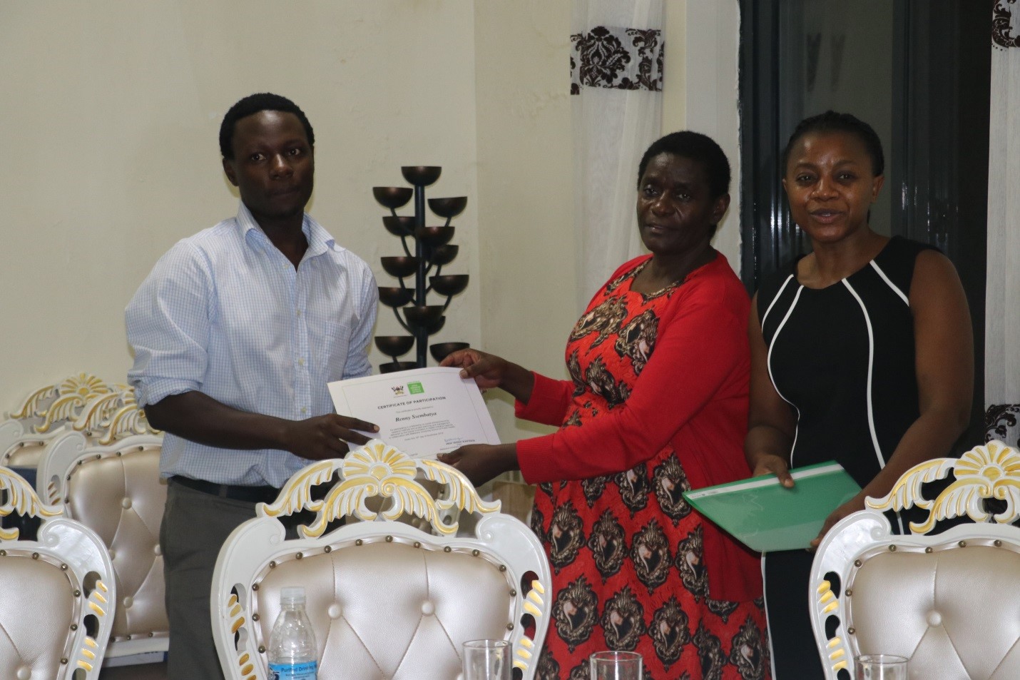 One of the participants receives a certificate from the Guest of Honour, Ms. Jennifer Muwuliza, the Asst. Commissioner in the Ministry of Science, Technology and Innovations.