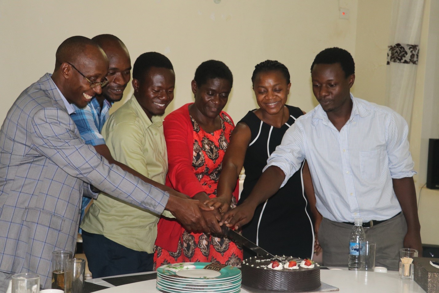 Some of the trainees join the Guest of Honour, Ms. Jennifer Muwuliza, (third left) and the SIHI Project Lead, Dr. Phyllis Awor (second left) to cut the cake.