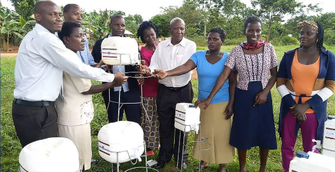 Teachers at Bishop Kauma Zzinga Primary School receiving hand washing facilities from Dr. David Musoke (extreme left) and the LC III Chairperson of Bussi sub county, Wakiso district (Mr. Stanley Kabuye – centre with white shirt).