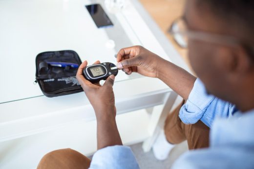 Young man using digital glucometer at home Diabetes control